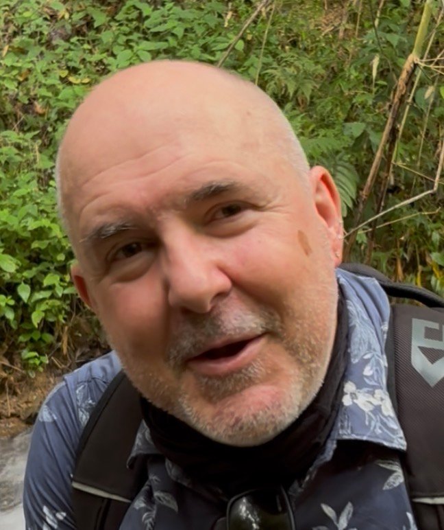 Psychologist for NDIS participants | David the Psychologist @hennessyclinicalpsychology smiling outdoors, wearing a patterned shirt and backpack, symbolising approachability and support for NDIS participants in building functional and emotional capacity.