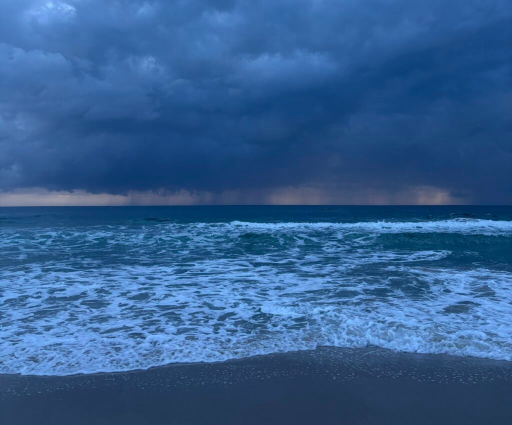 Storm clouds over the ocean, symbolising the heaviness and intensity often felt during depression, with a glimpse of light on the horizon suggesting hope and change.