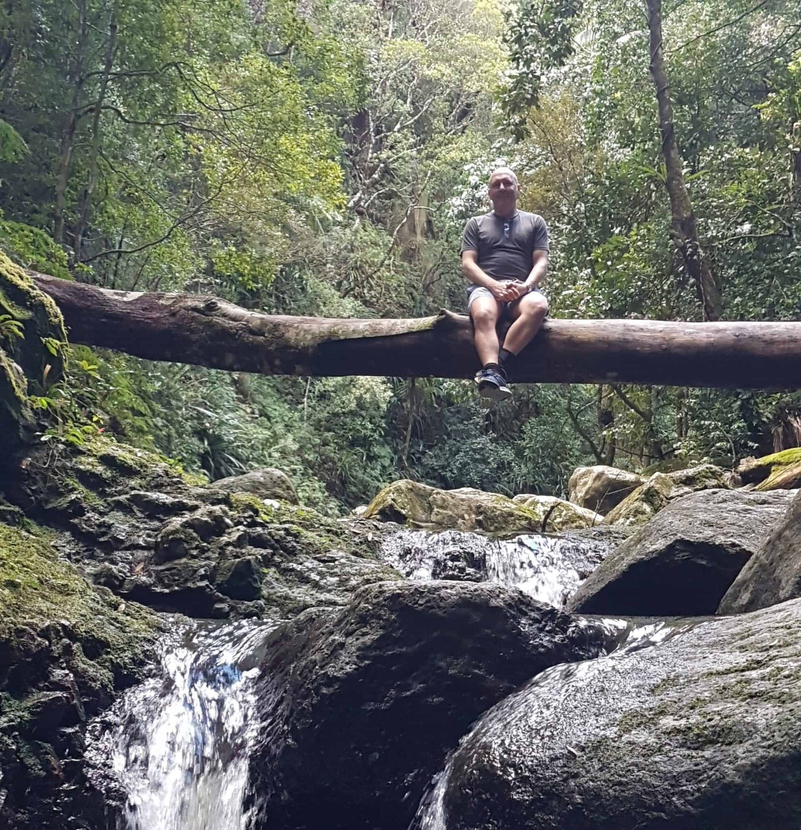 David Hennessy, Clinical Psychologist, enjoying nature beside a rainforest waterfall on the Gold Coast, reflecting his appreciation of time outdoors and wellbeing.