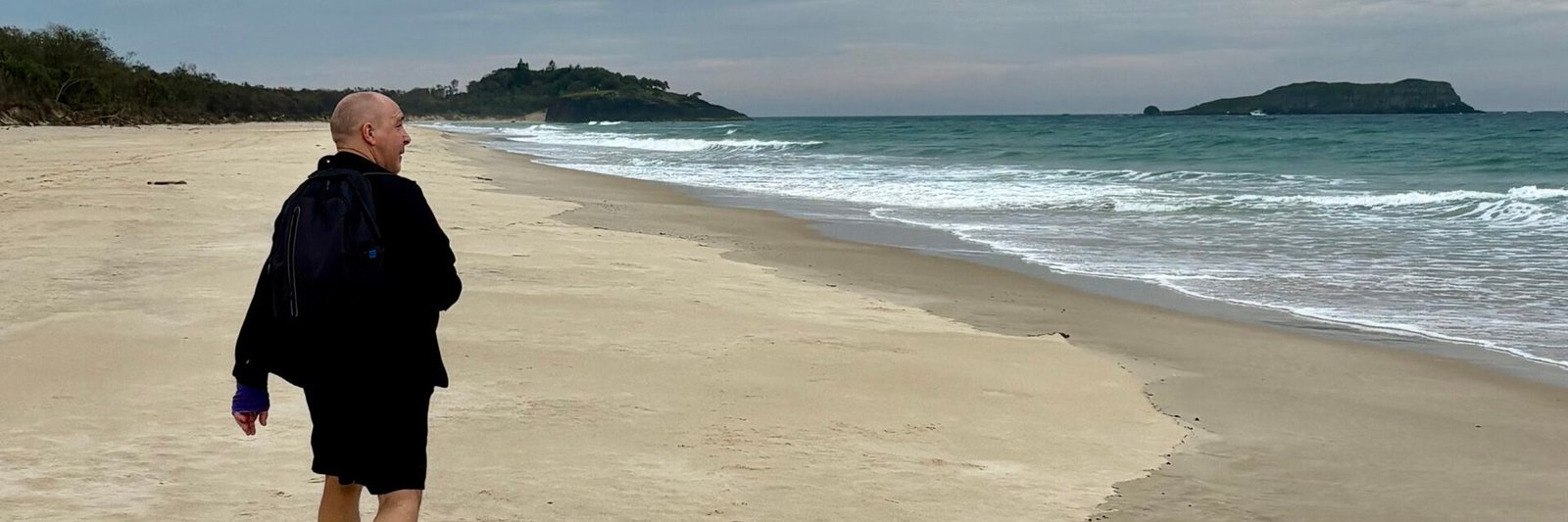 Acceptance versus change | David the Psychologist walks alone along a quiet beach under a grey sky, symbolising acceptance, reflection, and gentle change.