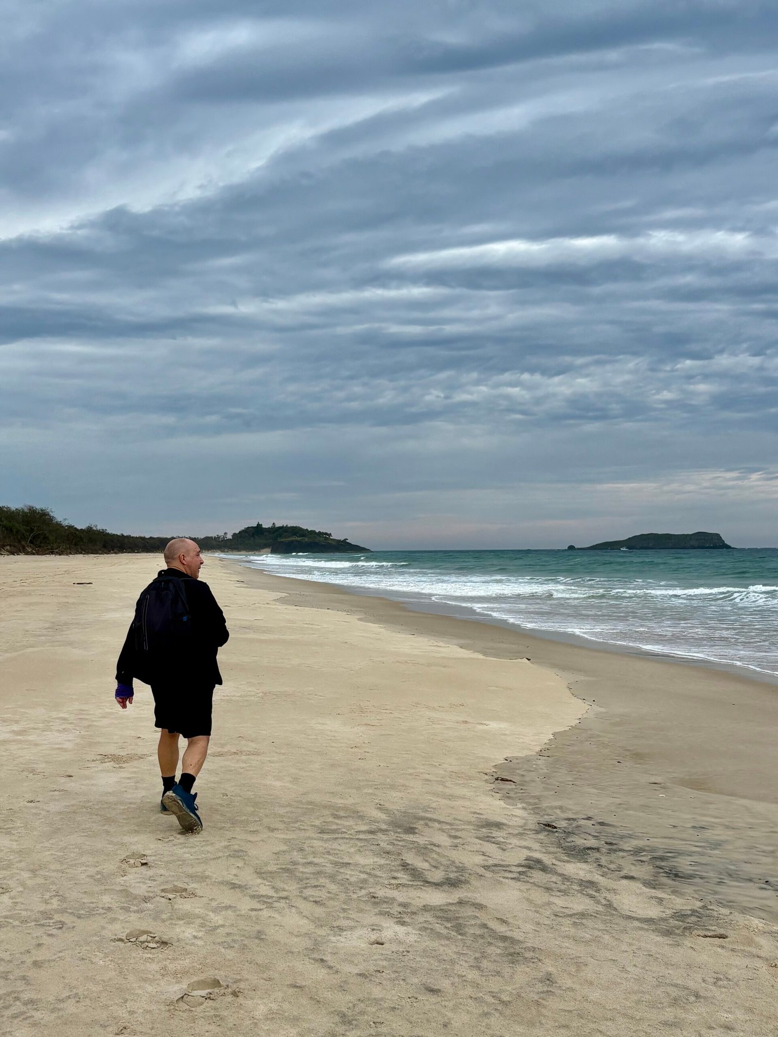 Acceptance versus change | David the Psychologist walks alone along a quiet beach under a grey sky, symbolising acceptance, reflection, and gentle change.