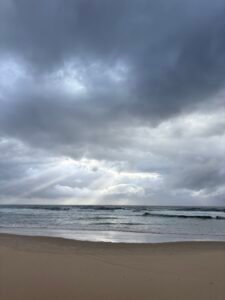 Stormy ocean under dark clouds with light breaking through, symbolising strong emotions and the process of emotional regulation.