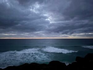Dark storm clouds gathering over ocean waves and a rocky coastline