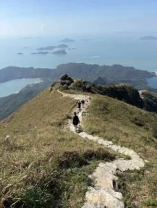 People walking along a mountain path overlooking the coast