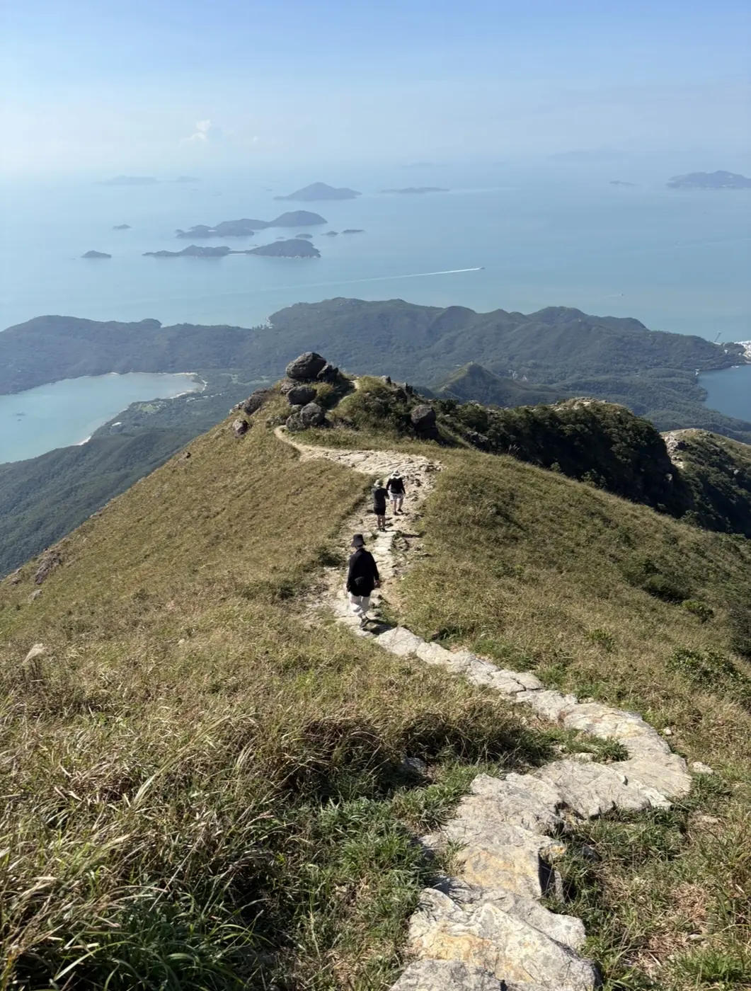 People walking along a mountain path overlooking the coast